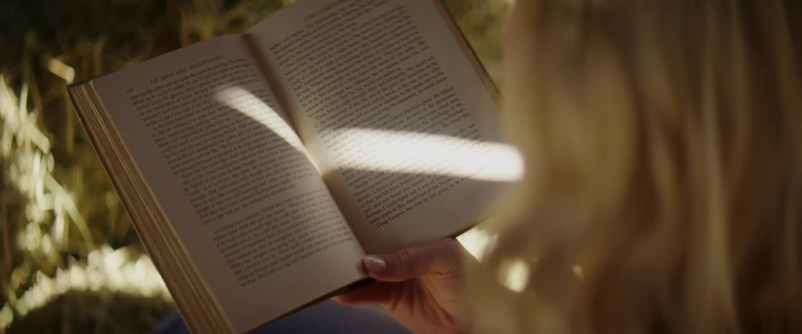 A woman sits outside and reads a book