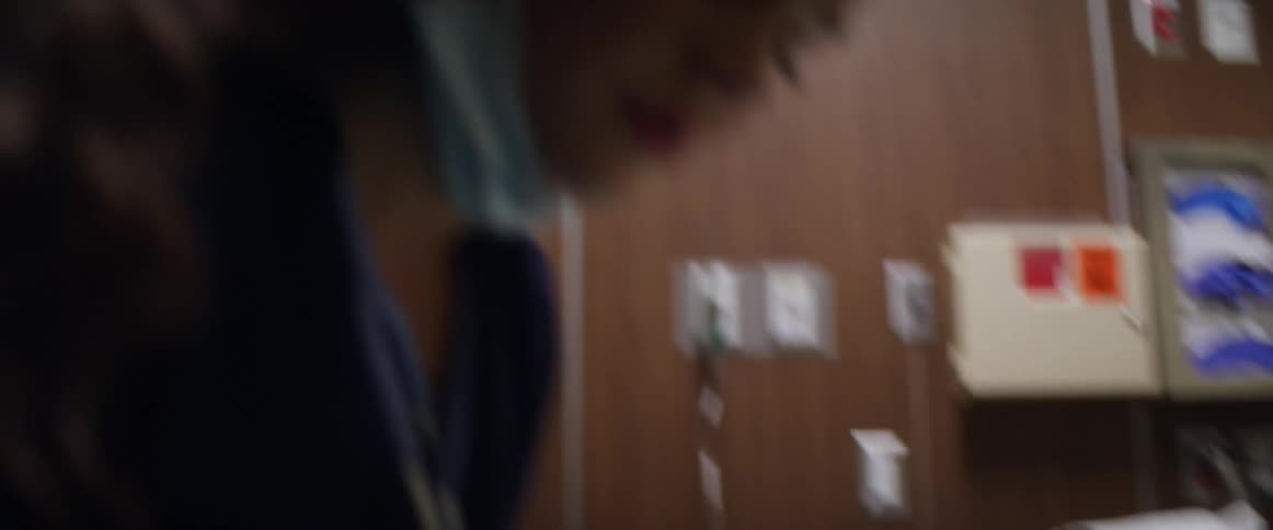 A patient lies in a hospital bed and nurses quickly work on her