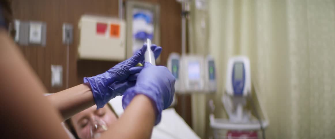 Nurses work on a person in the hospital bed