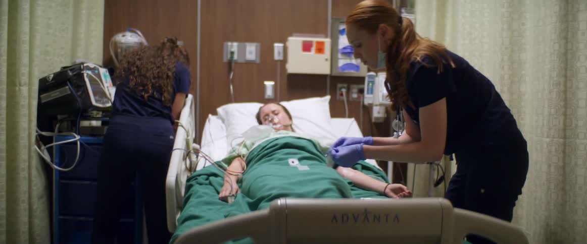 Two nurses act rapidly to take care of unconscious patient in hospital bed