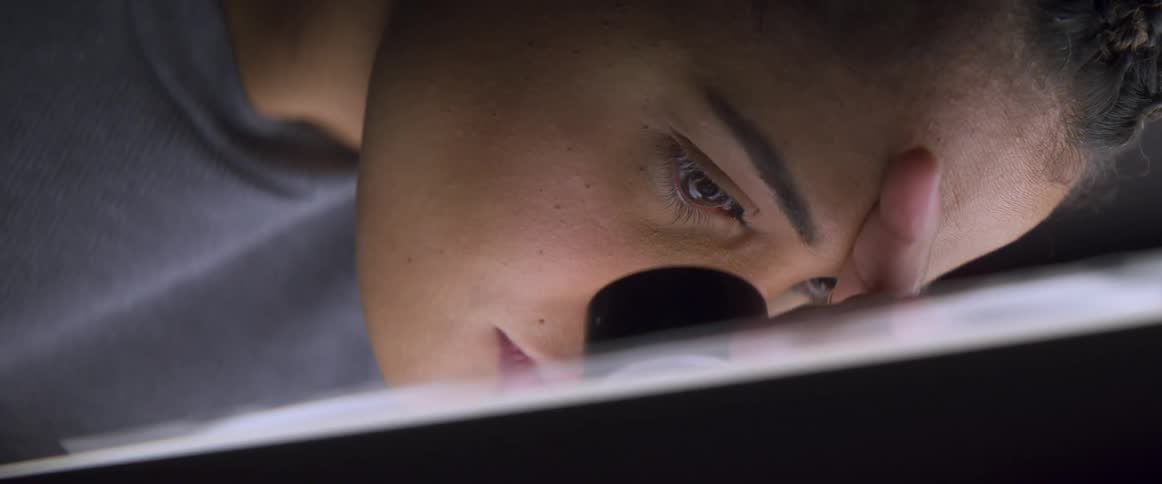 A woman leans down and looks in to a microscope