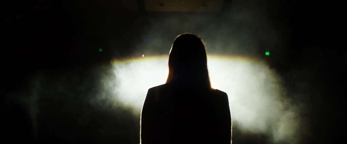 A woman walks towards a bright light and smoke