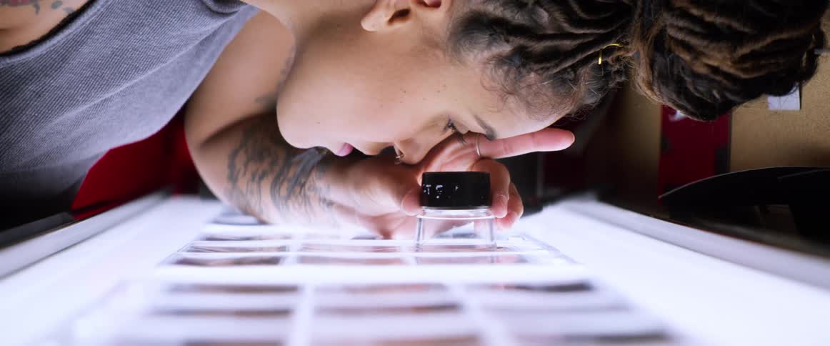 A black woman uses an eyepiece to study frames of pictures on a lighted table