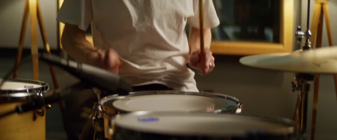 Male drummer plays drums at home at night