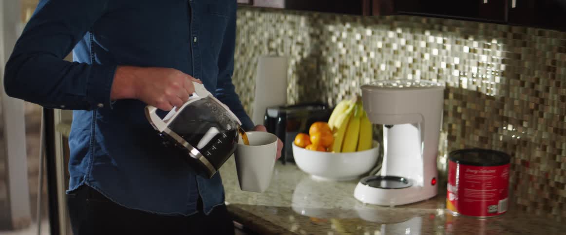 Man pours coffee into a cup in the kitchen
