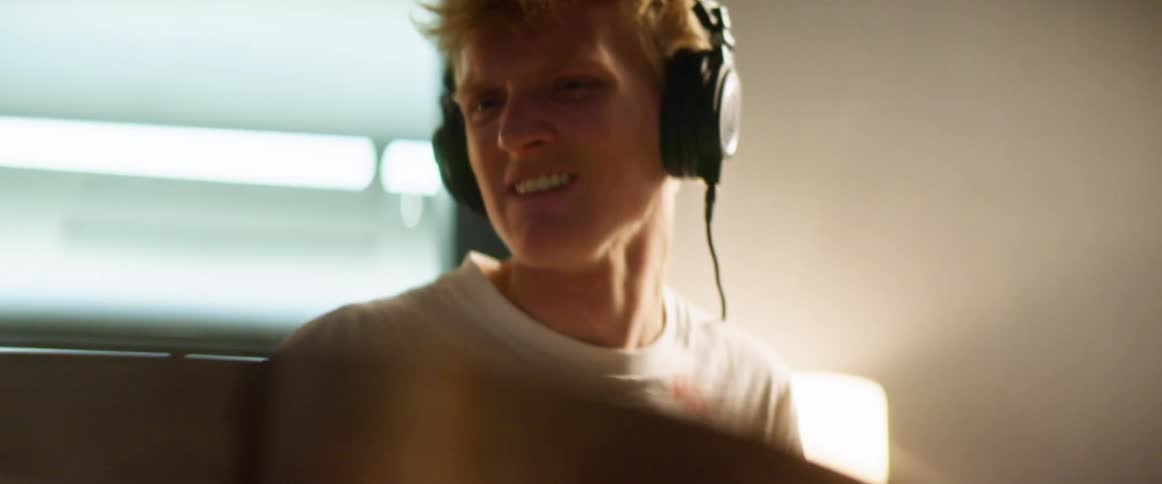 Male drummer wearing headphones plays drums indoors