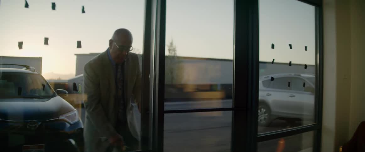 Man in a suit opens the door of a store