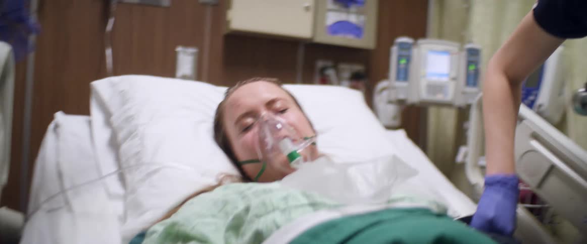 Two nurses working to hook up equipment to woman on ventilator