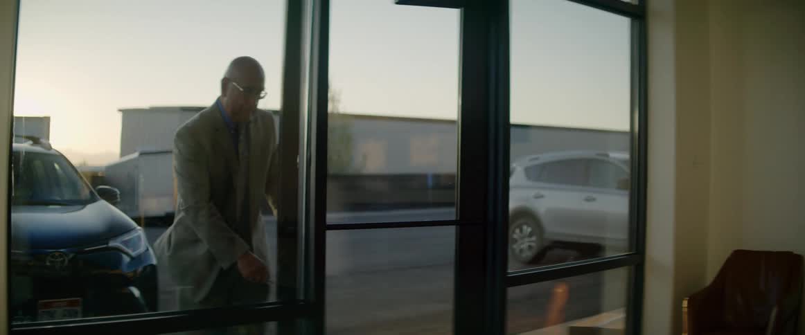 Man in a suit opens the door of a store