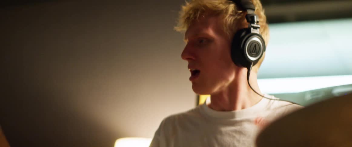 Man wearing headphones plays drums