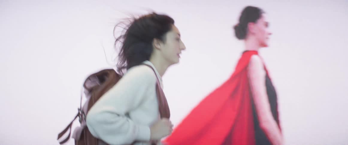 A woman runs in a building as she looks at her watch