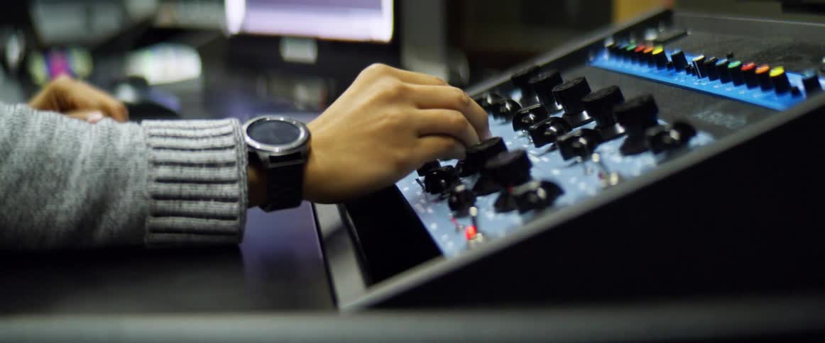 A man sits at a desk in a recording studio working with audio equipment and a computer