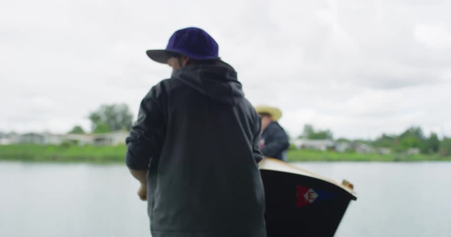 Father and son carry rowboat out to the water