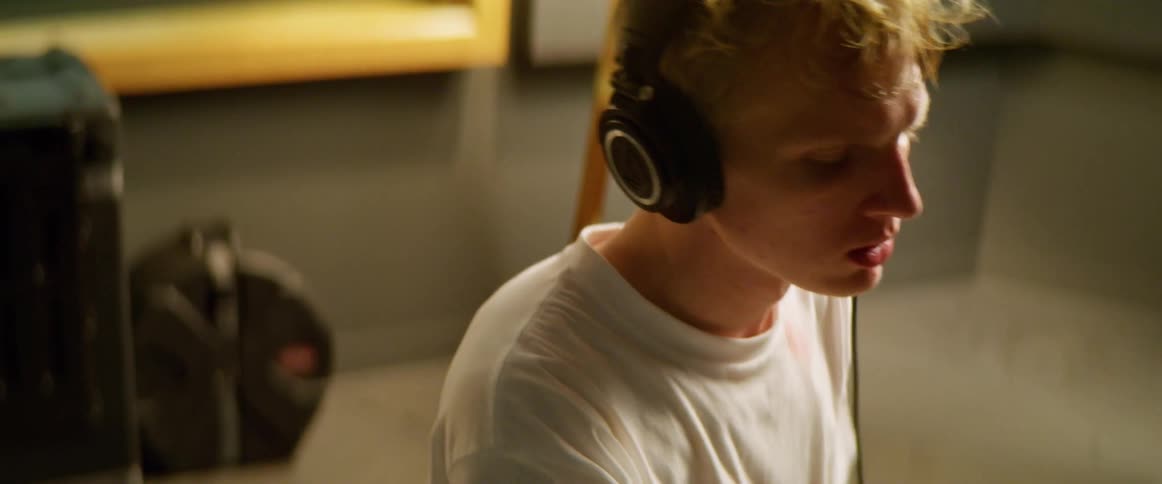 Male places headphones over his ears and begins playing the drums along with the music