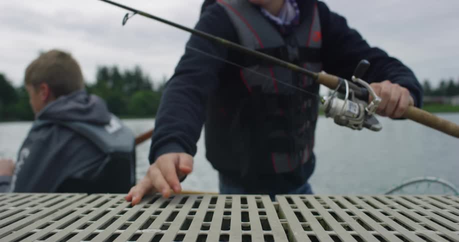 Two boys in boat on lake with fishing rod