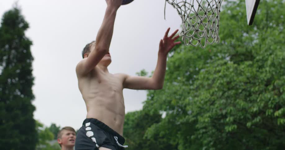 Two boys playing basketball on neighborhood street