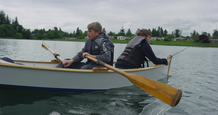 Two white teens out on a rowboat in a lake