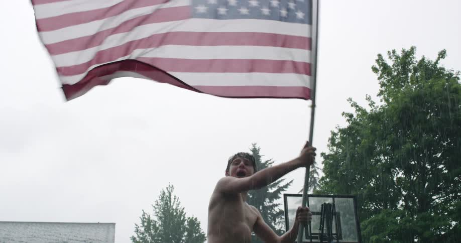 Passionate teenager waves the USA Flag in the rain on the streets of a neighborhood