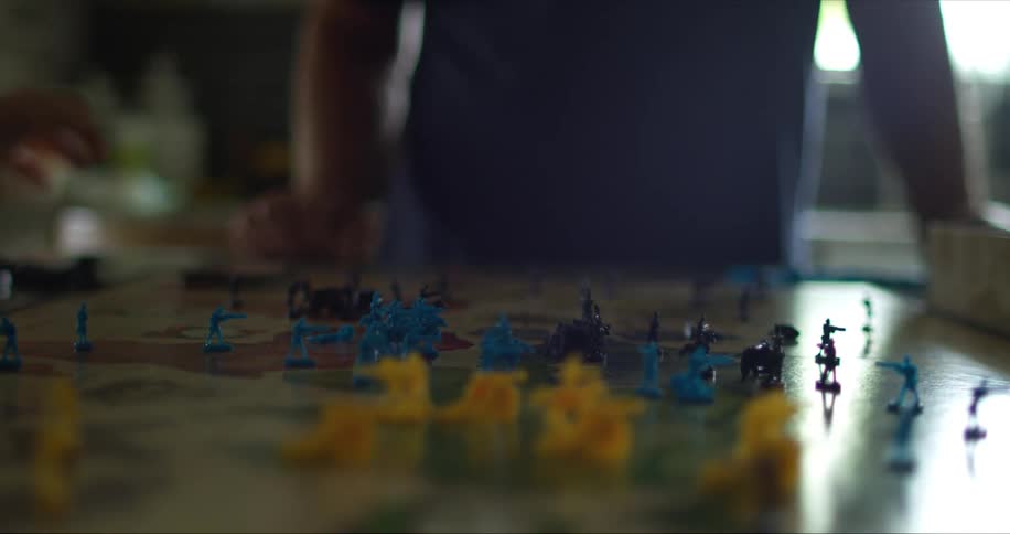 Two white men stand at a table and play a board game