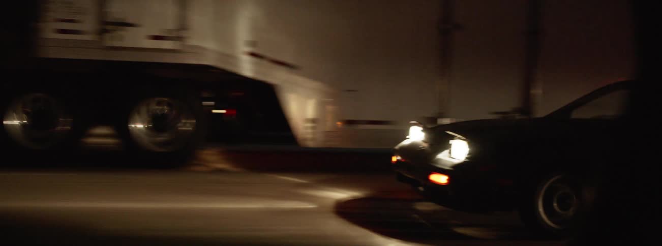 A car drives past a big rig hauling a trailer on a highway