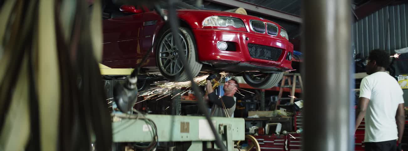 Mechanic watches second mechanic work on car undercarriage