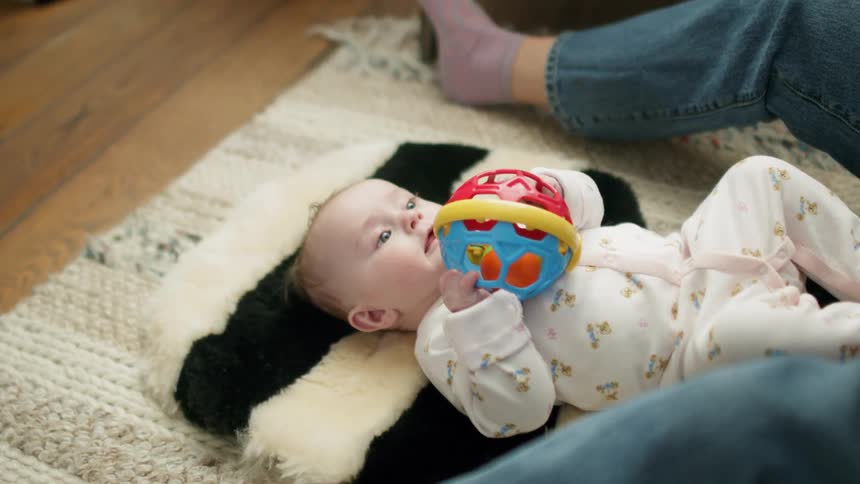 A parent sits with a baby on the floor