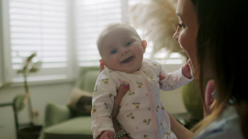 A mother and her infant daughter laugh and kiss