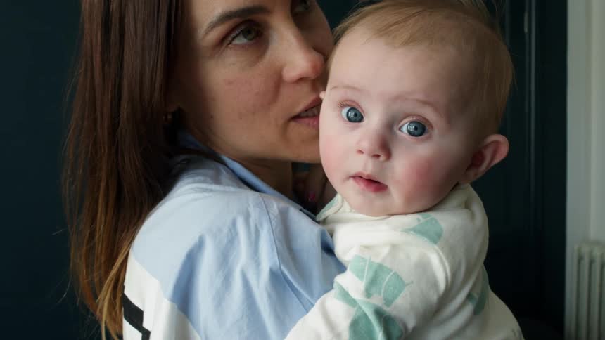 A mother holds her baby and rocks back and forth while talking