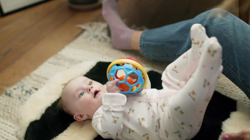 Mother plays with her baby while sitting on the floor