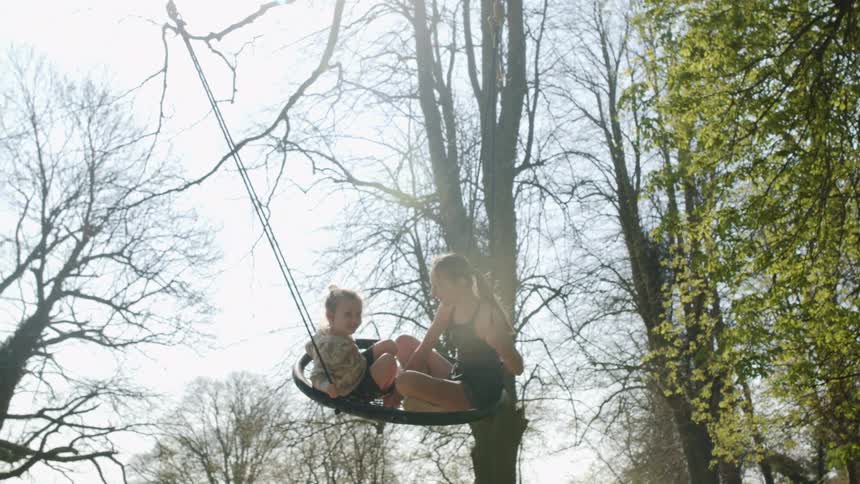 Two girls swinging together on tree swing