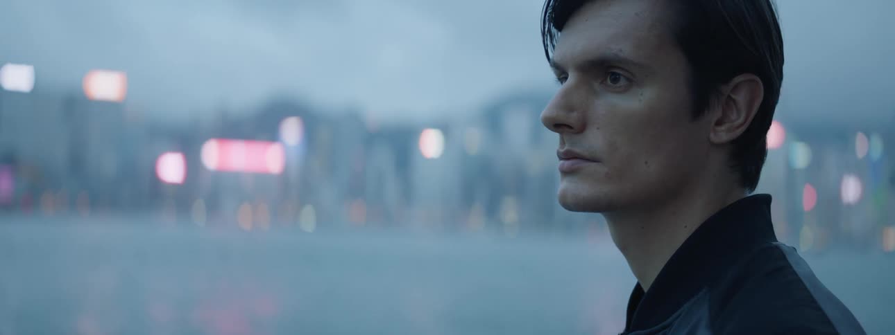 A man stares across the water to look at a city skyline at dusk