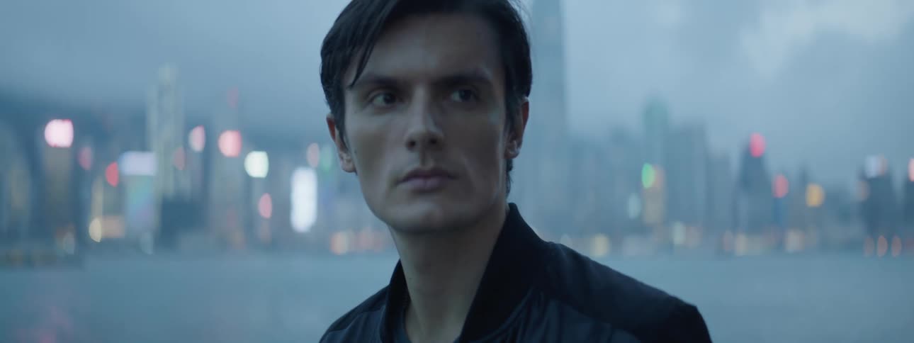 A man is standing outdoors by a city skyline