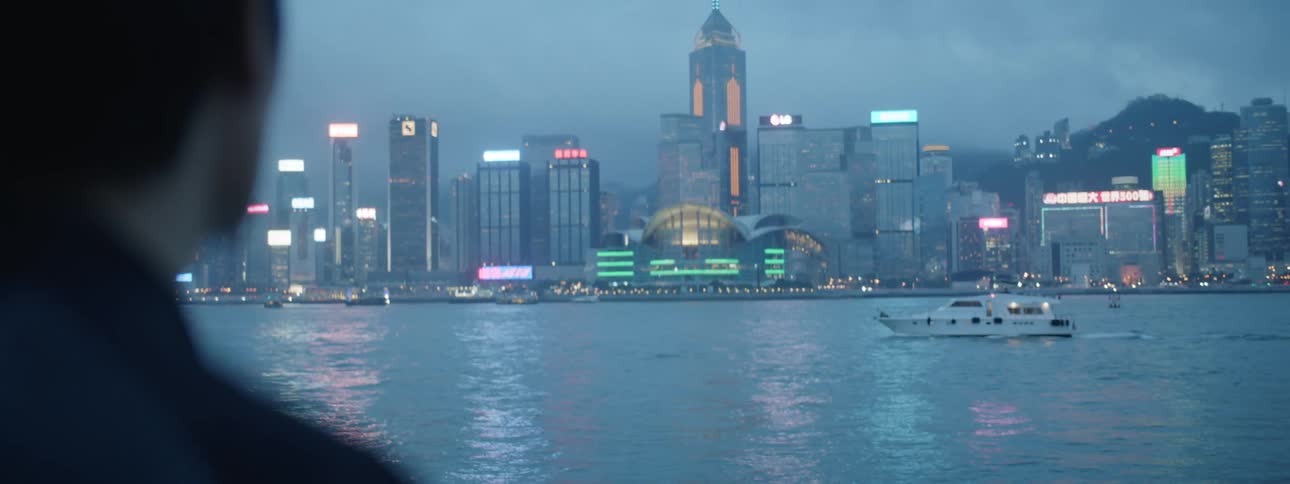 Man watches the illuminated buildings across the sea at dusk