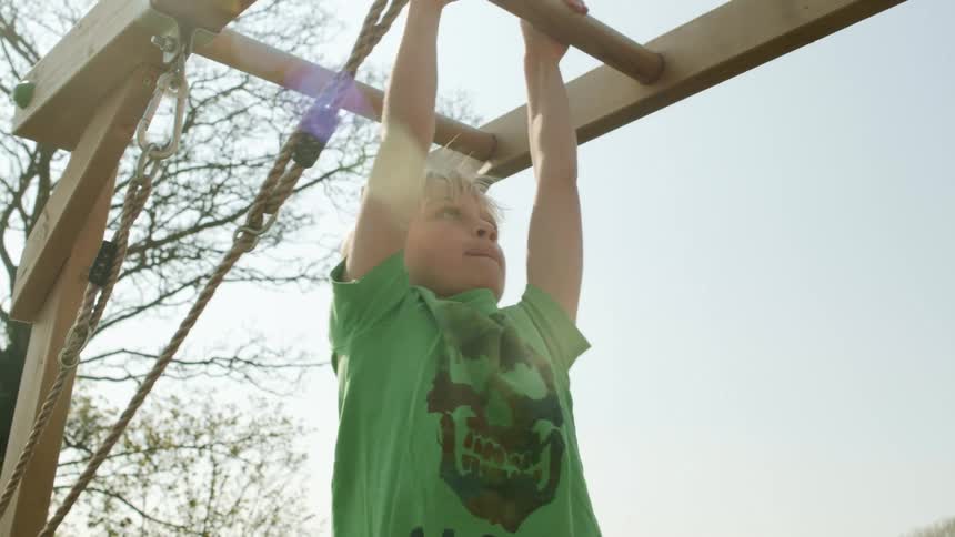 Little boy climbing across monkey bars on playground