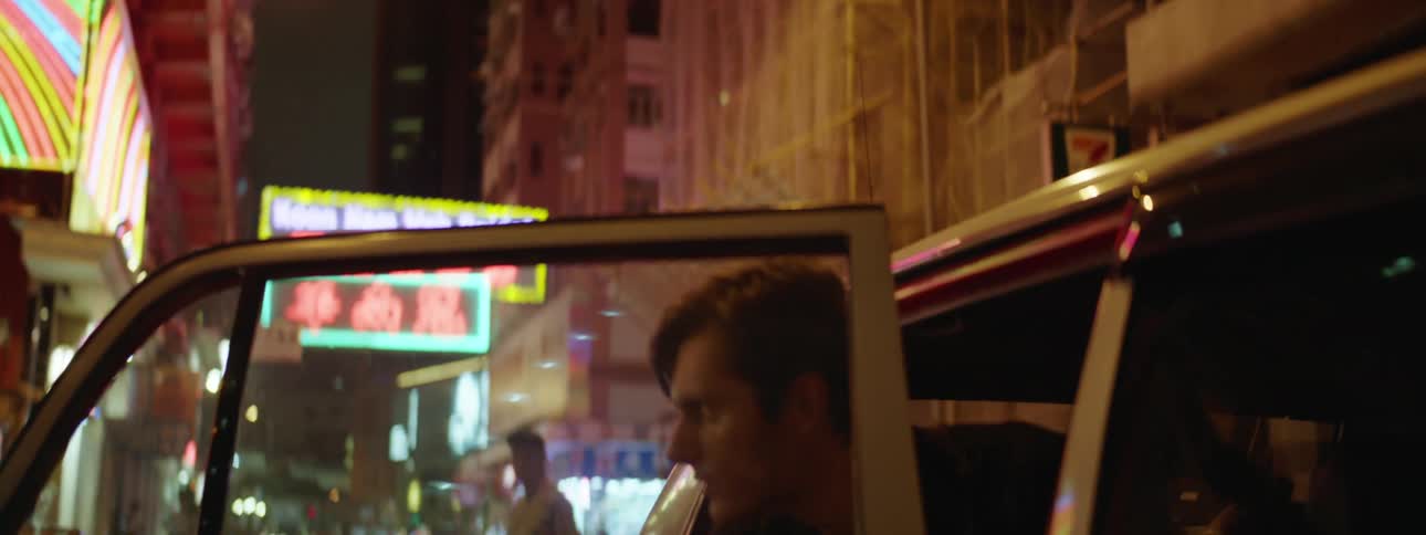 Man gets into taxi on city street at night