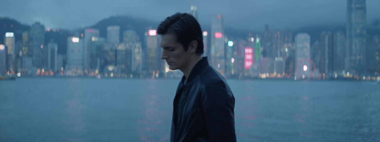 A man looking out over the bay of a metropolis before turning away