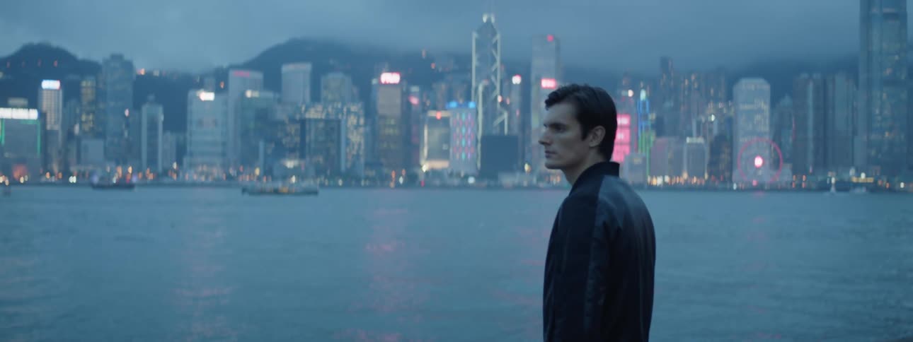 A man is standing outdoors and the city skyline is in the background