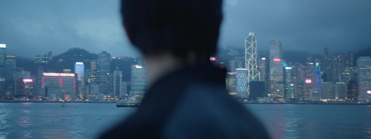 Man watches the illuminated tall buildings across the sea