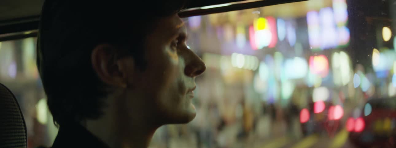 Close up of a man riding a bus through city downtown at night