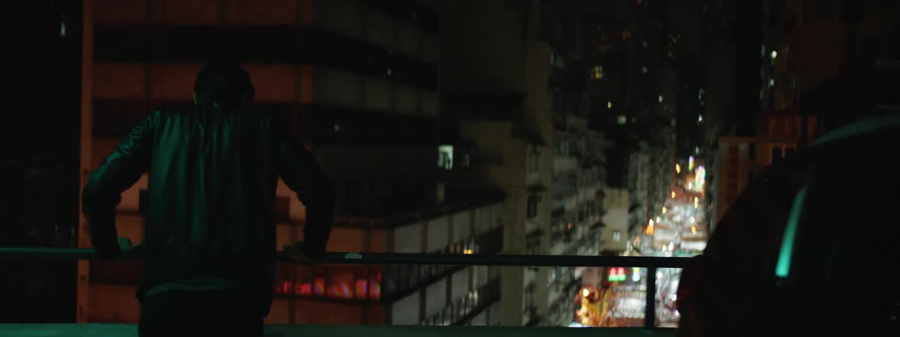 A white man runs to a railing overlooking a major street in a the downtown part of the city