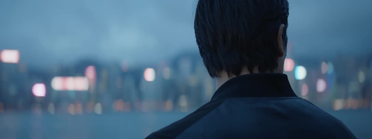 Man watches the illuminated city across the sea at dusk