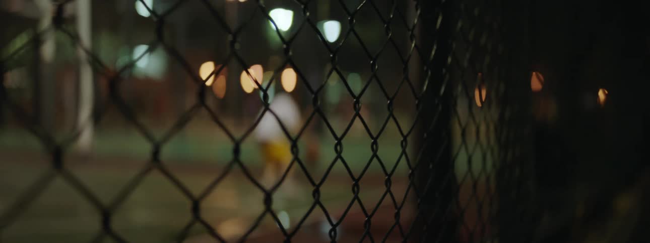 Man plays basketball in the basketball court at night