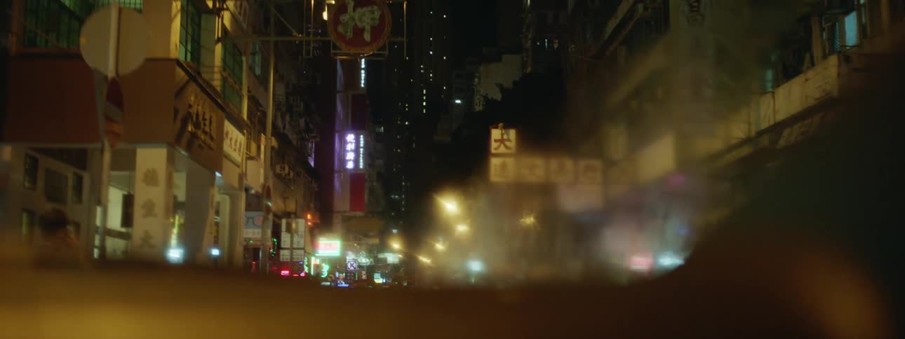 A city street with traffic lights and building lights shining at night through a car window
