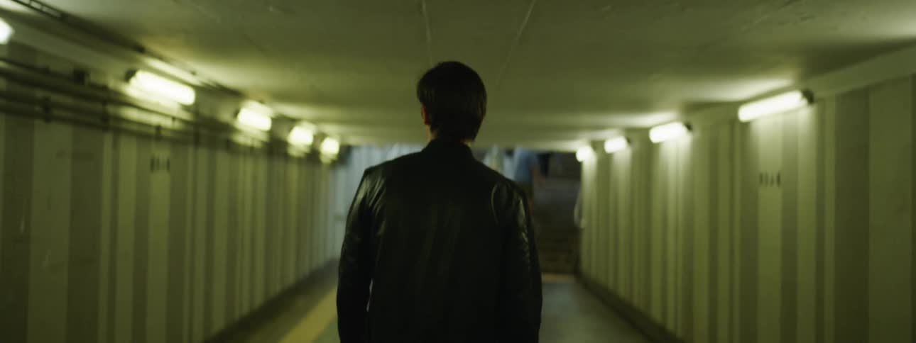 A man walks through a hallway tunnel that leads to steps into a stadium