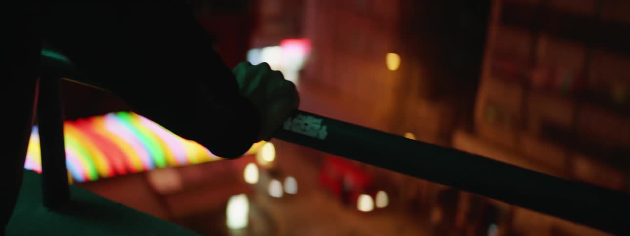 Person standing at railing overlooking city streets at night