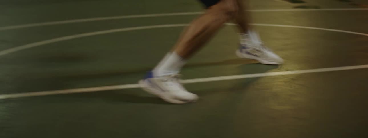 Man is playing basketball by himself on an outdoor court and shoots basket