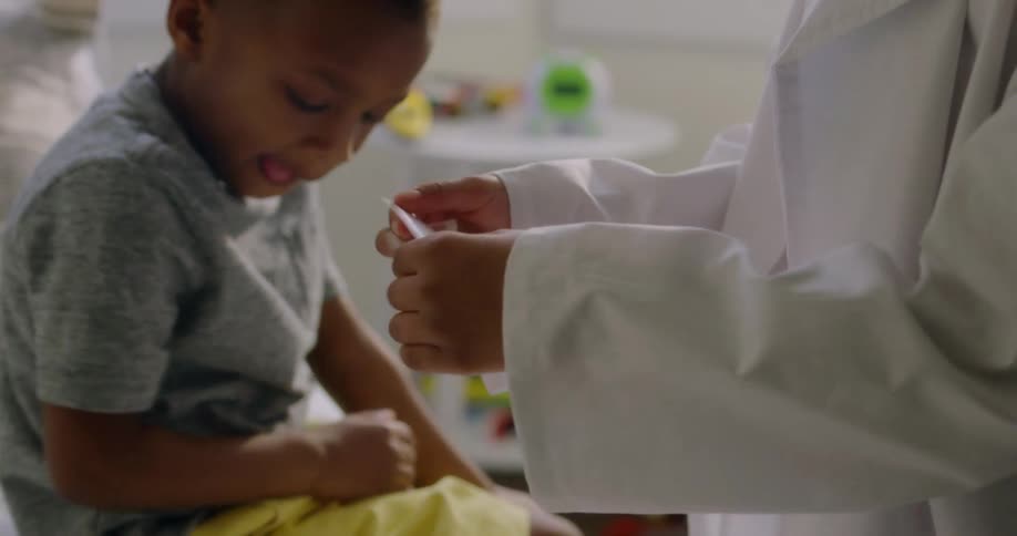 A doctor puts a bandaid on a little boy