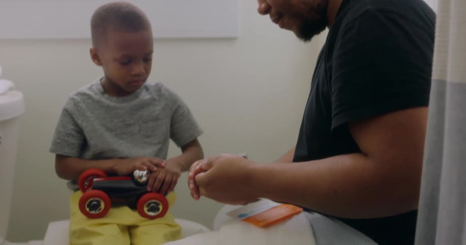 A dad high fives his son after putting a bandage on his leg in the bathroom