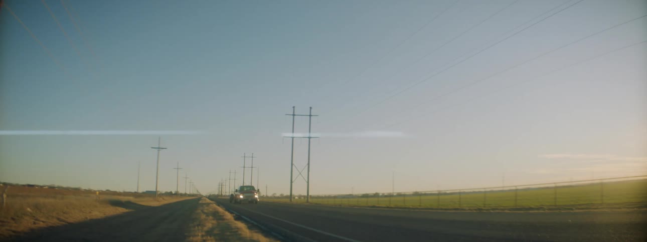 Pickup trucks driving on a country road at dawn