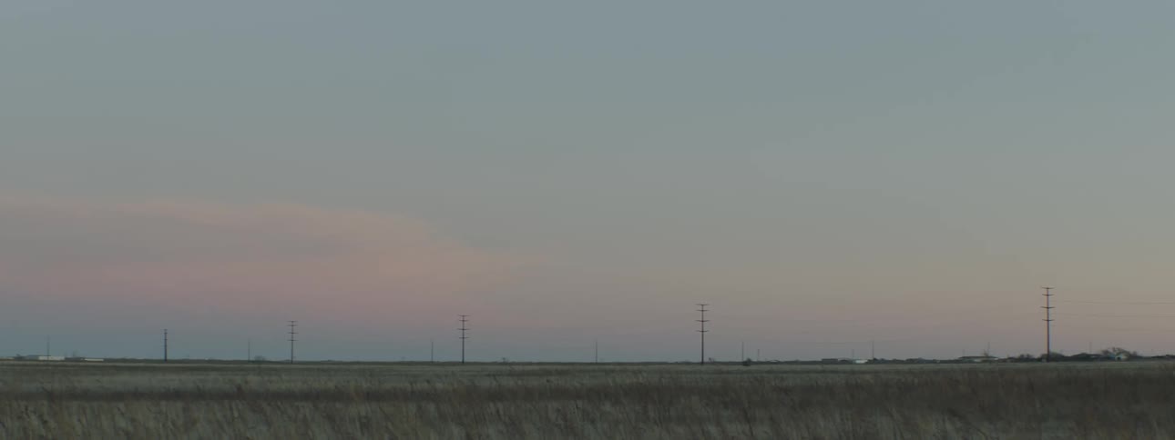 Grassland punctuated by transmission towers and a few buildings